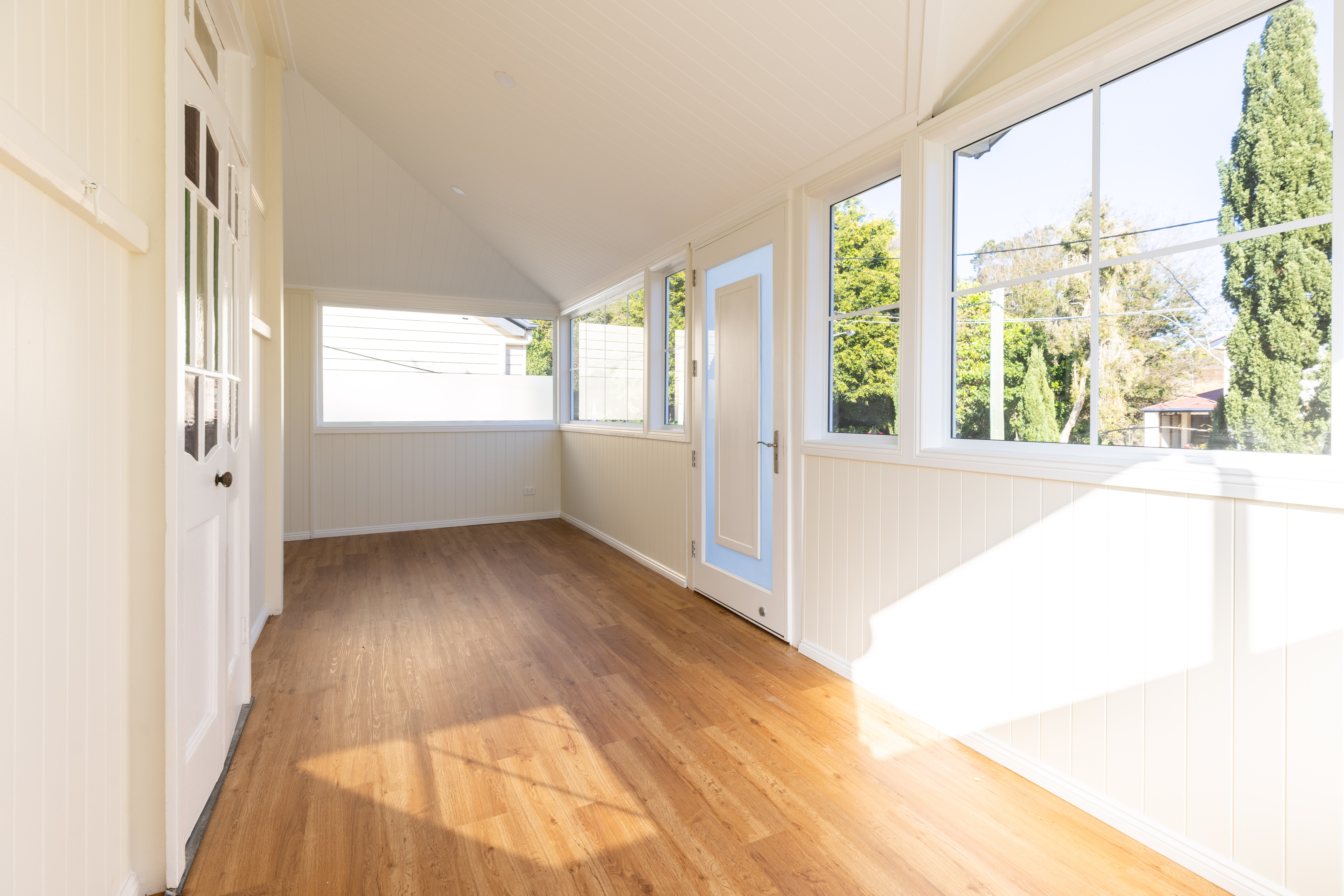 Enclosed verandah home extension South Brisbane — bright new living space with white joinery and garden views