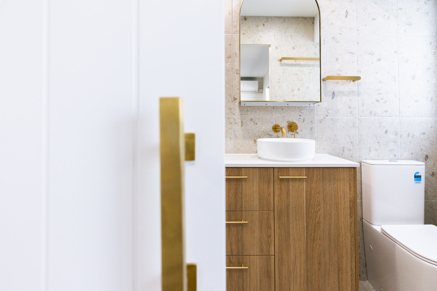 Modern bathroom with brass fixtures and timber vanity