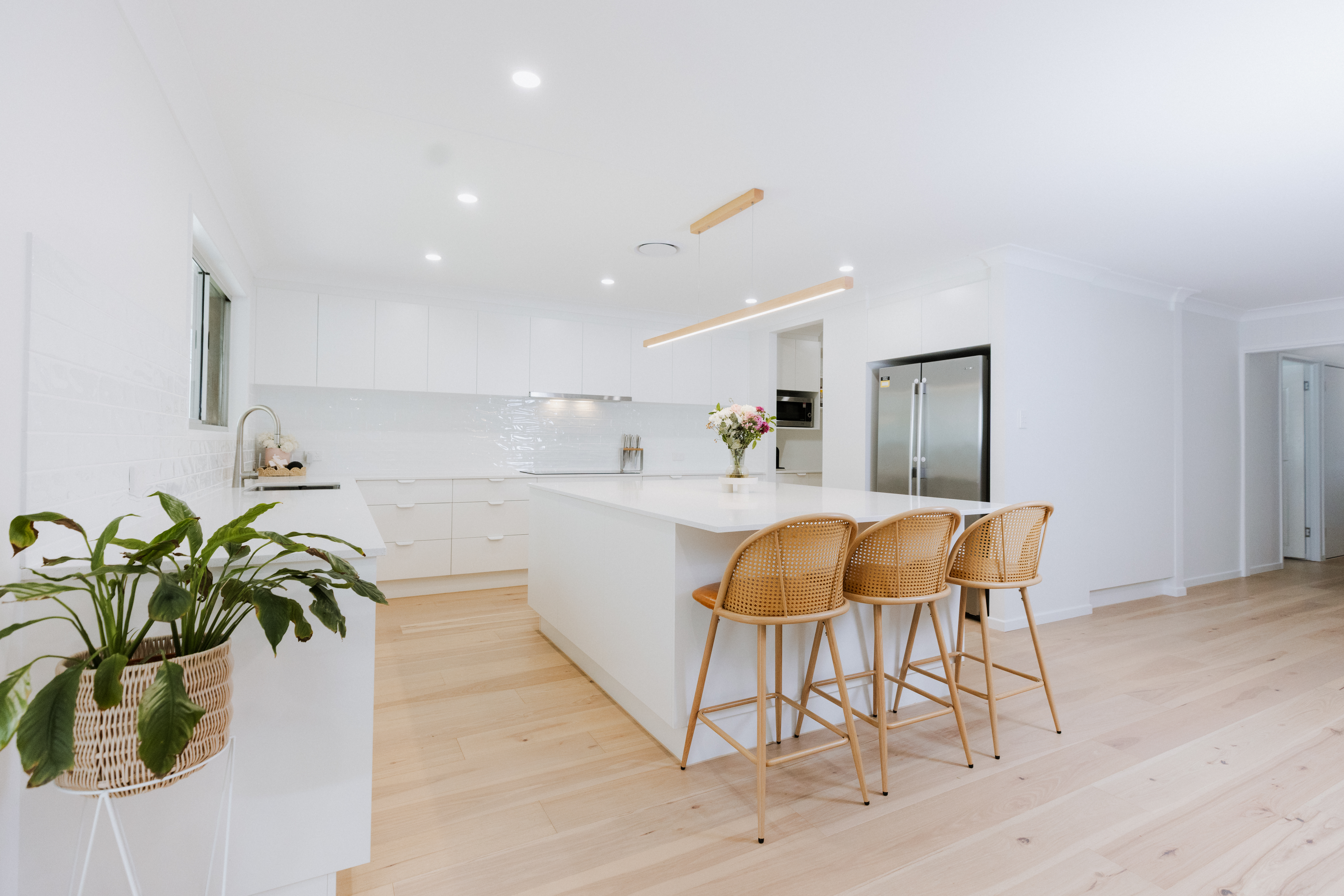 Wide angle view of renovated kitchen in Rochedale South with white island and pendant light