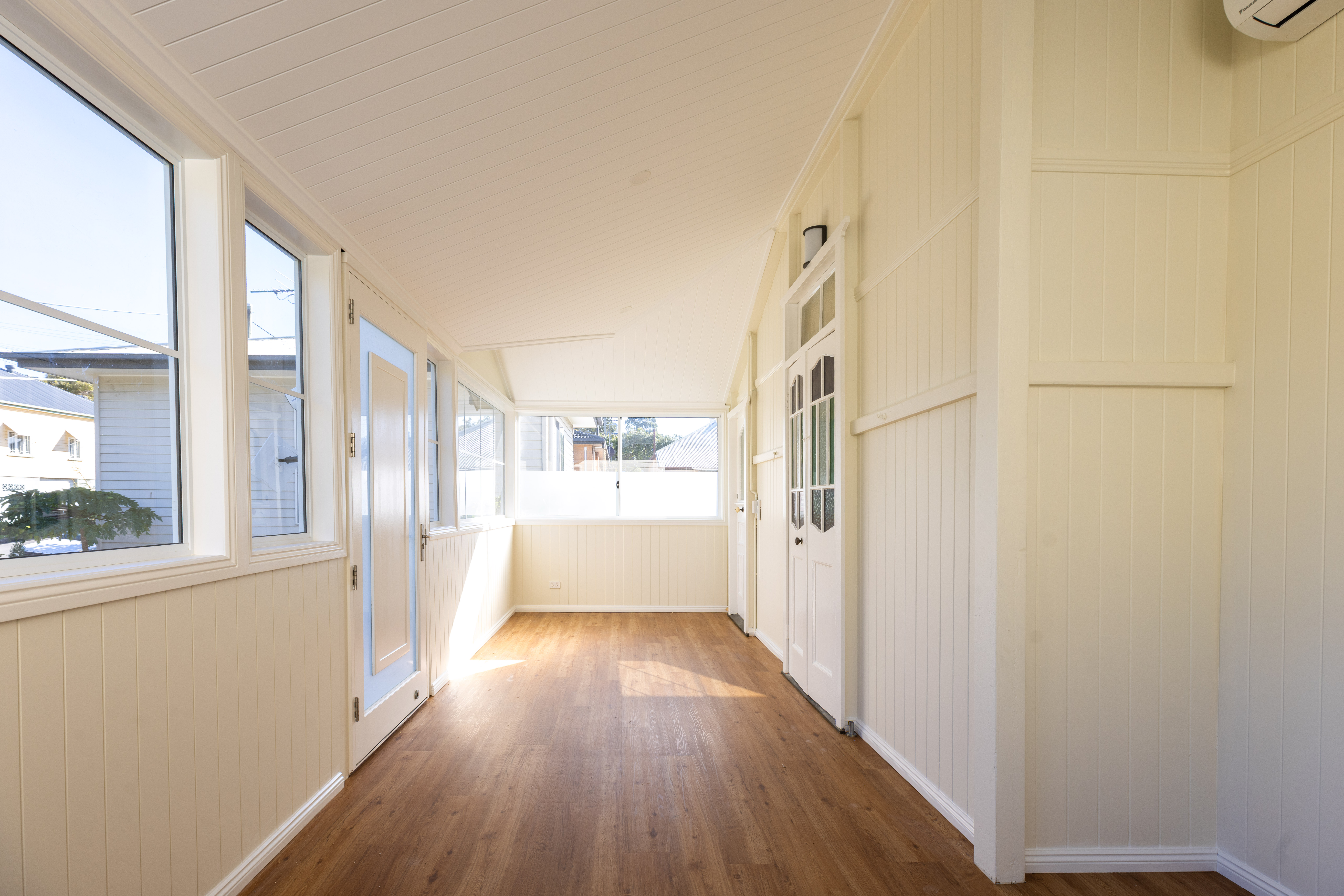 Completed sunroom extension South Brisbane — timber floors and full-height windows throughout enclosed verandah